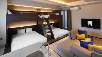 A modern hotel room with bunk beds, a sofa, a TV, and a kitchenette.