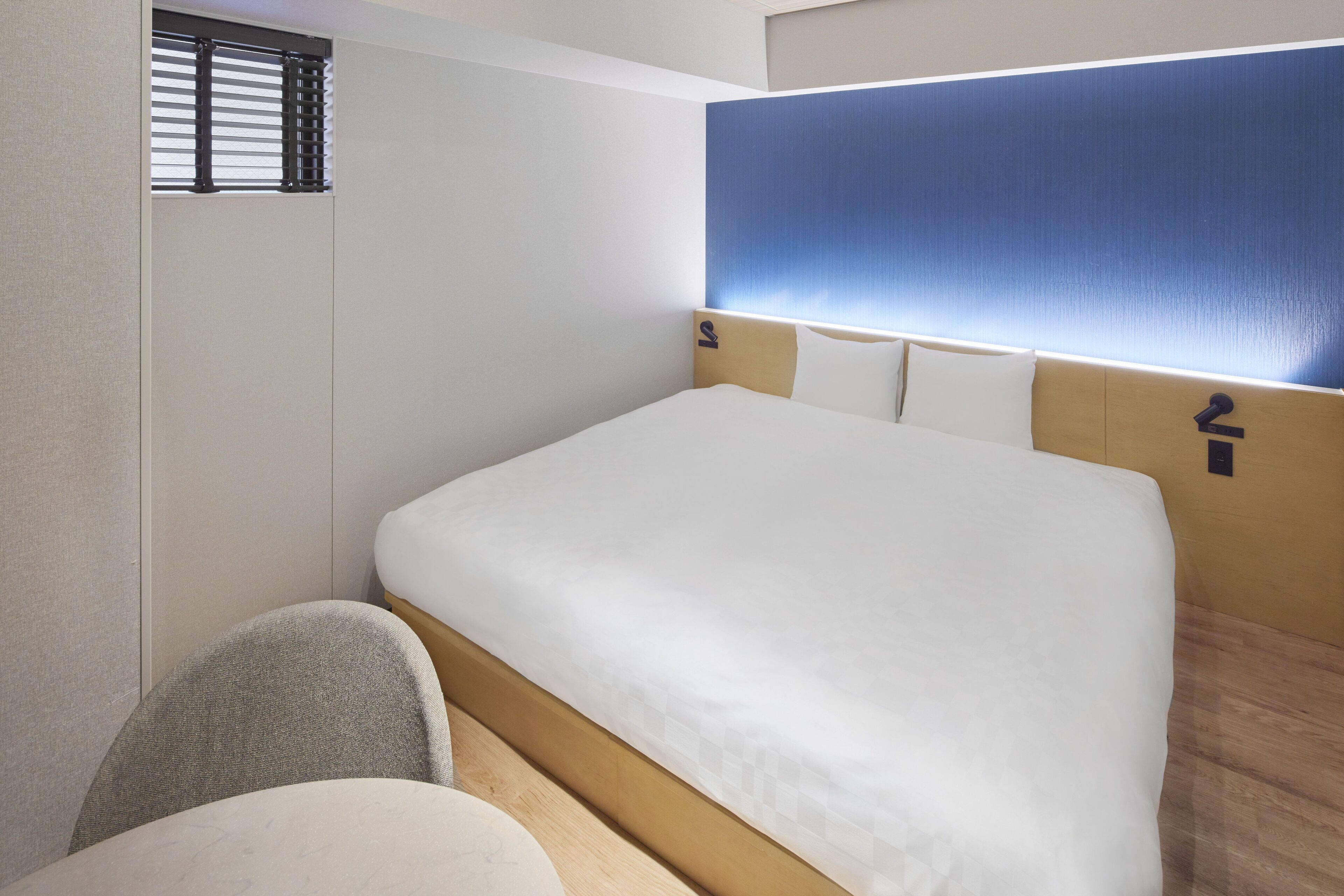 A hotel room with a large bed, a small round table, and a chair.