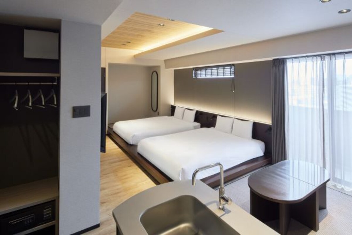 Una habitación de hotel moderna con una cama grande, un escritorio pequeño, un lavamanos integrado y un vestidor.