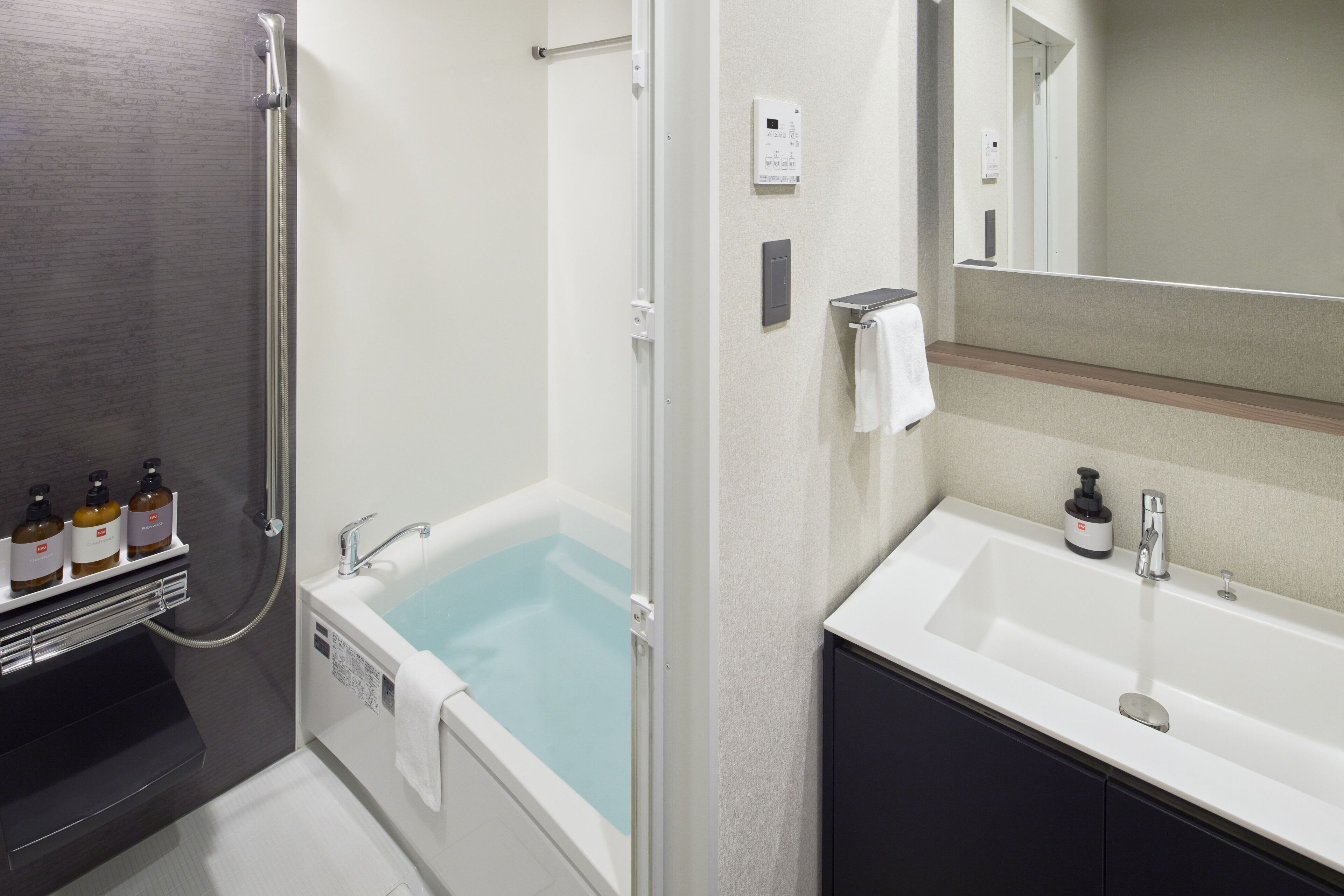 Un baño moderno con una bañera, una ducha, un lavabo y un espejo.