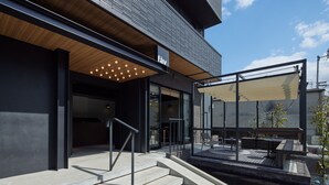 A modern building with a wooden ceiling, a glass entrance, and outdoor seating.