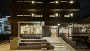 A modern building with a coffee shop on the ground floor, featuring a glass facade and a staircase leading to the entrance.