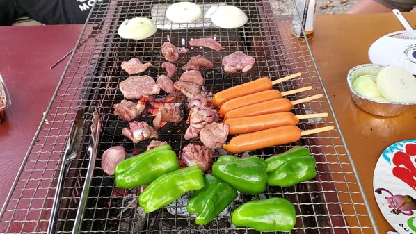 Una parrilla con carnes y verduras cocinándose.