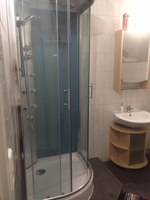 A glass-enclosed shower with a white sink and a mirror above it.