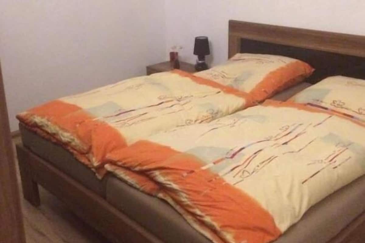 A single bed with a wooden frame and a patterned bedspread.