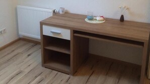 Une pièce avec un bureau en bois, un radiateur et un plafond en pente.