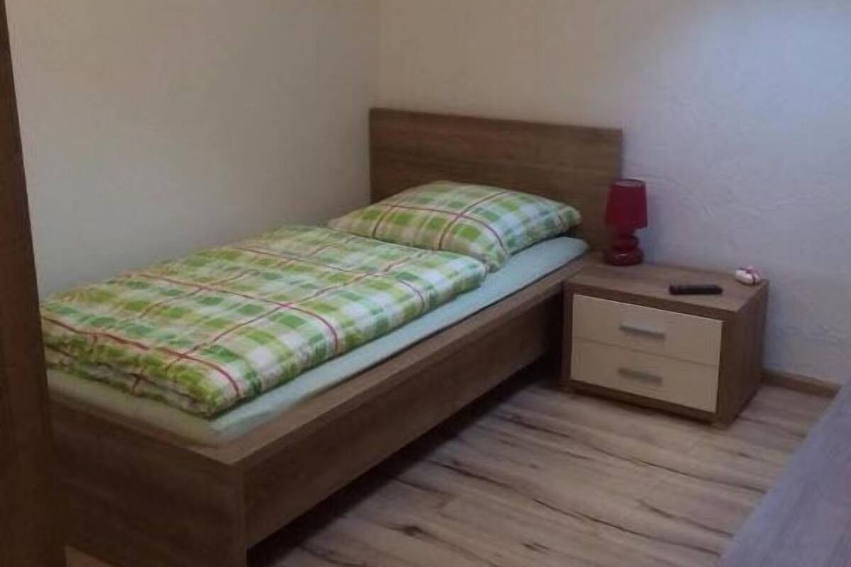 A small, single-bed room with a slanted ceiling and a skylight.