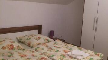 Ein Schlafzimmer mit einem Einzelbett, einem Kleiderschrank und einem kleinen Fenster.