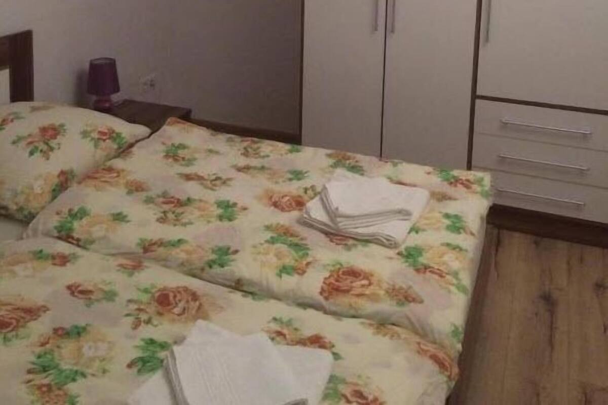 A bedroom with a bed, a wardrobe, and a nightstand.