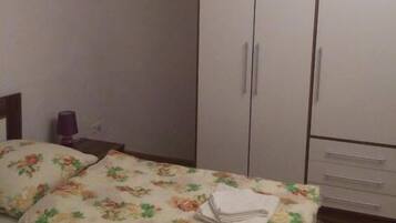 A bedroom with a bed, a wardrobe, and a nightstand.