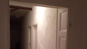 Un couloir étroit avec un plancher en bois et des murs blancs.