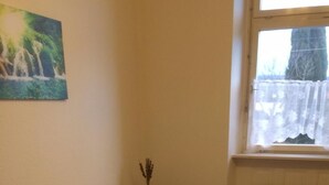 Une chambre à coucher avec un lit en bois, une table de chevet, un radiateur et une fenêtre donnant sur des arbres.