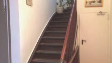 Eine Treppe mit Holzstufen und Geländer, die zu einer Tür mit einem kleinen Bild darüber führt.