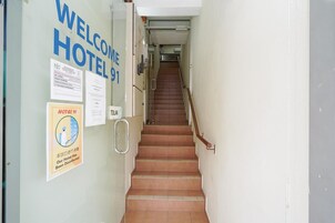 A hotel entrance with a staircase leading to the upper floor. There are signs on the wall indicating the hotel's name and a notice about recent disinfection.
