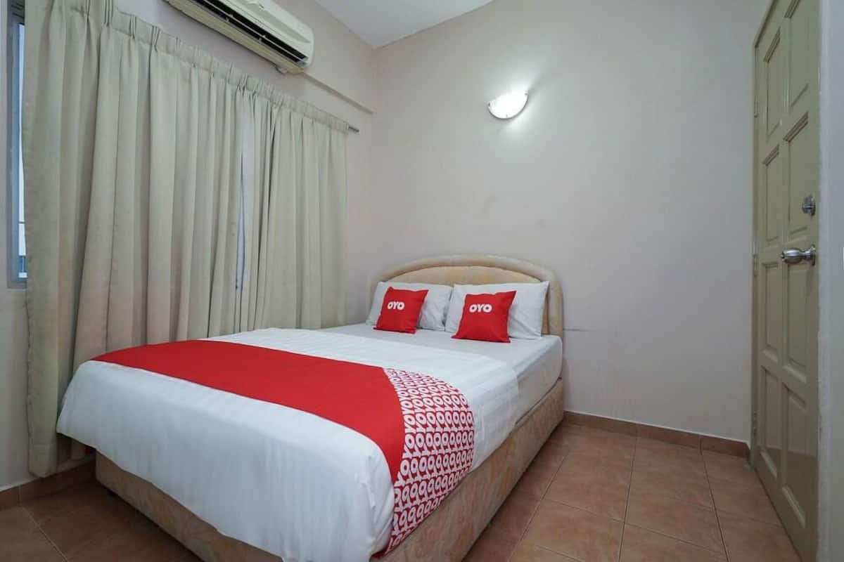 A hotel room with a bed, curtains, a door, and an air conditioning unit.