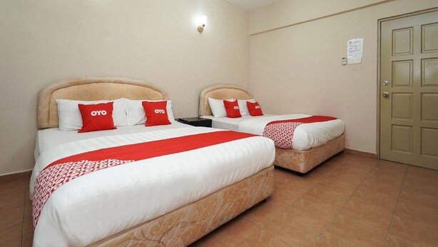 A hotel room with two beds, each with a red and white bedspread, and a beige door. - Hotel O 9 @ Kajang Town (Kajang)