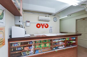 A reception area with a wooden counter, a clock, and a wall-mounted air conditioner.