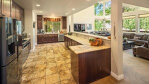 Una cocina amplia con armarios de madera oscura, una isla grande y un comedor con vistas al exterior.
