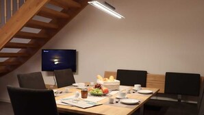 A conference room with a wooden table, chairs, a television, and a breakfast setup.