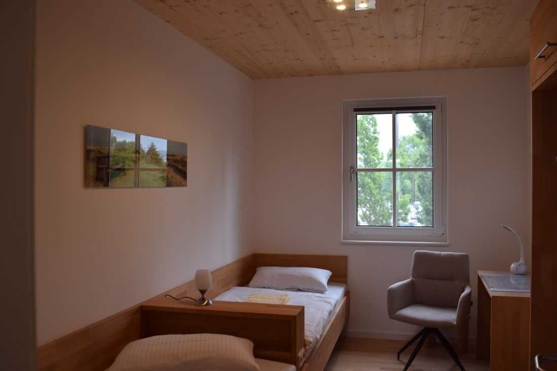 Une chambre avec un plafond en bois, un lit, un bureau, une chaise et une fenêtre.