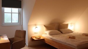 A bedroom with a bed, bedside tables, a chair, and a window with blinds.