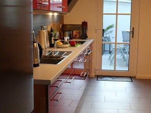 A modern kitchen with a large window, a door leading to an outdoor area, and a tiled floor.