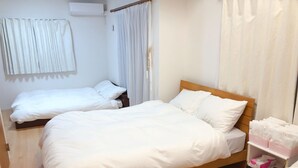 A hotel room with a large bed, a smaller bed, and a bedside table with a tissue box. - Tokyo Toneri Garden House-Stay (Tokyo)