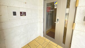 A hotel entrance with a glass door, a PayPay payment terminal, and directional signs. - BiBi Hotel Convention Bay (Ginowan)