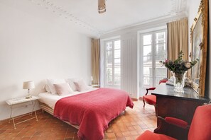A hotel room with a bed, bedside table, chair, dresser, mirror, and a window with curtains. - Bonne Nuit Paris (Paris)