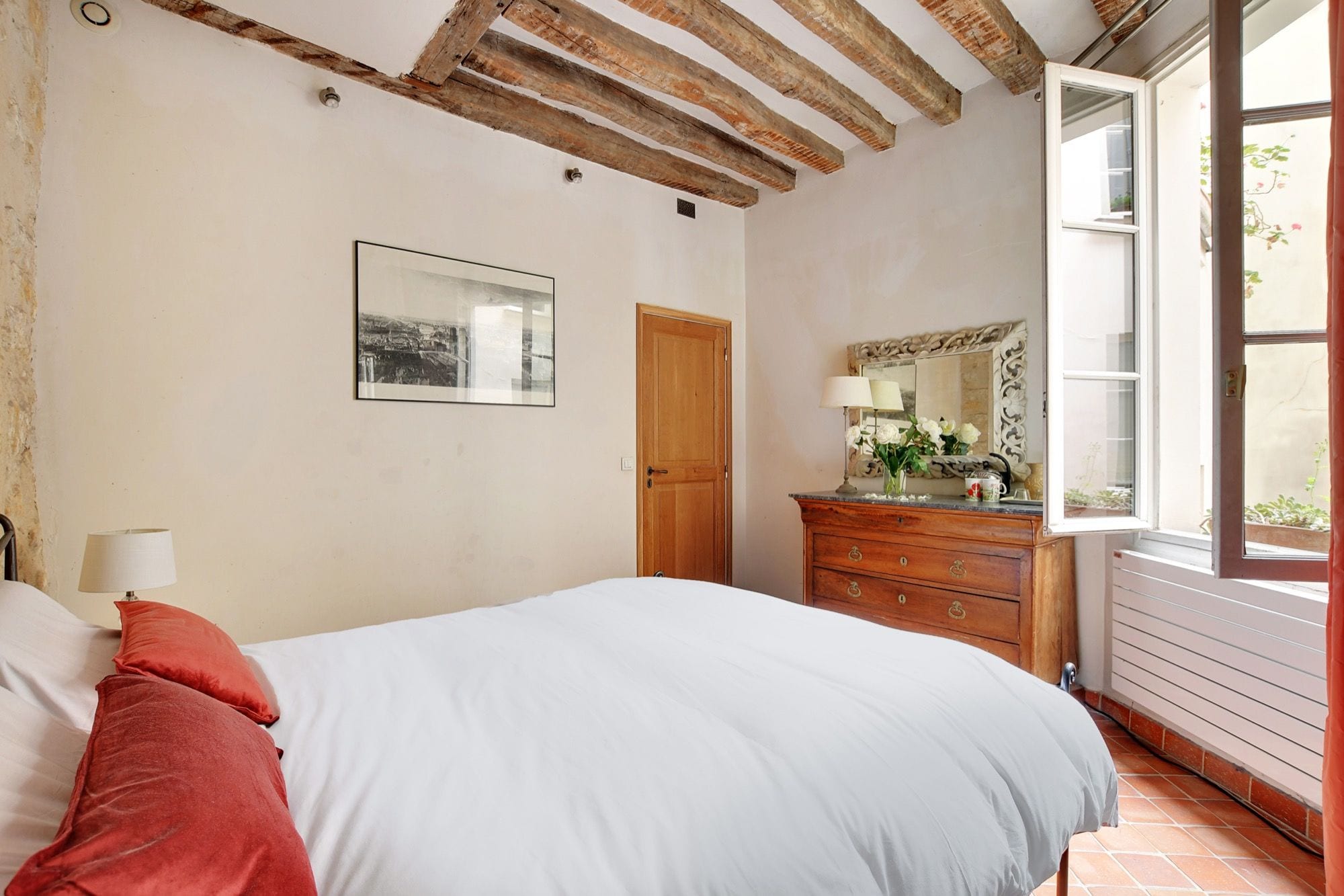 Une chambre à coucher avec un lit, une commode, un miroir et une fenêtre.