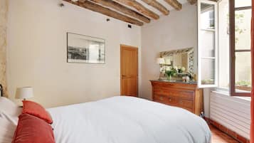 Une chambre à coucher avec un lit, une commode, un miroir et une fenêtre.