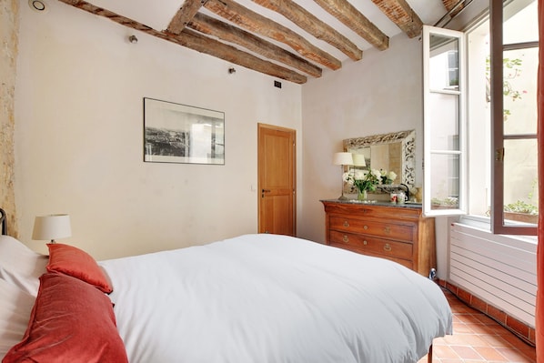 Une chambre à coucher avec un lit, une commode, un miroir et une fenêtre.