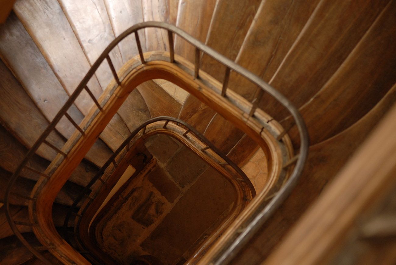 Un escalier en colimaçon avec une rampe en métal, des marches en bois et un mur en bois.