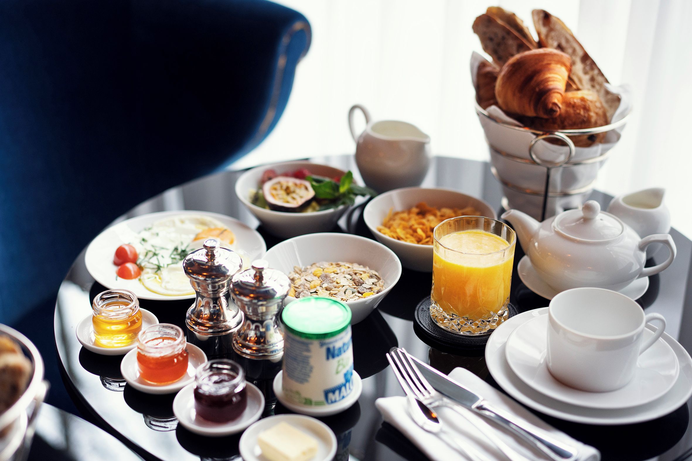 Een ontbijfwagen met croissants, cornflakes, fruit en een glas sinaasappelsap.