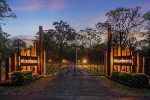 A gated entrance with 'Mirambeena' signs, a paved path, and surrounding trees.