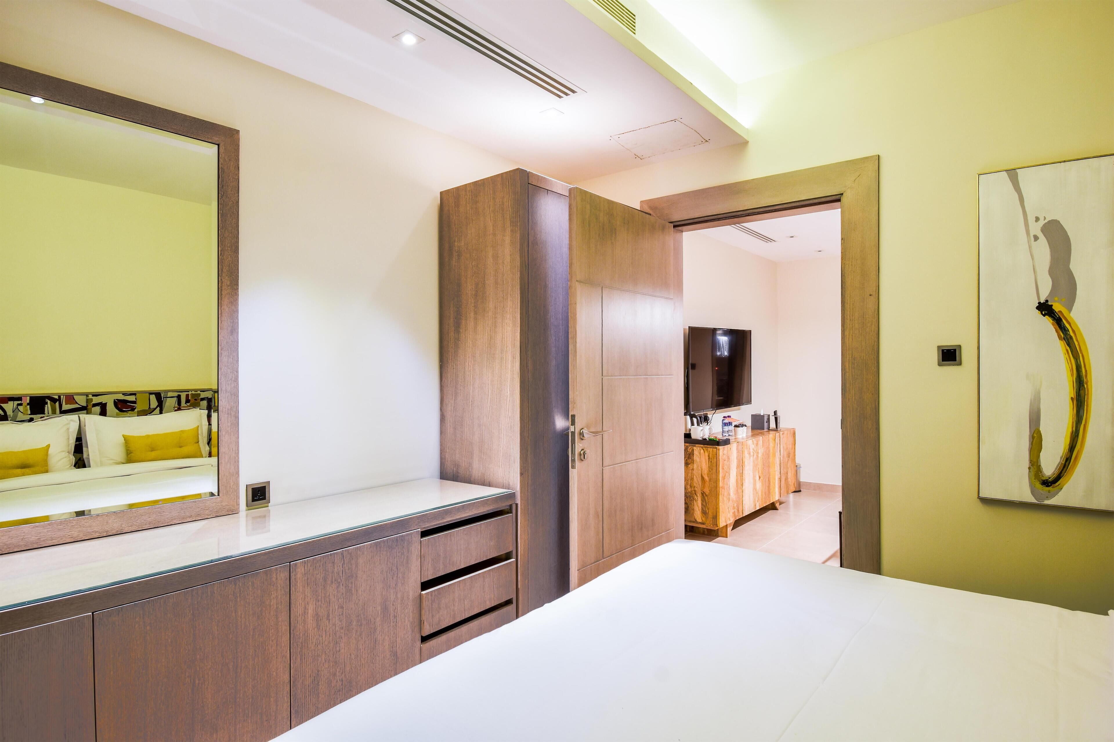 A hotel room with a large bed, a wardrobe, a mirror, and a painting on the wall.