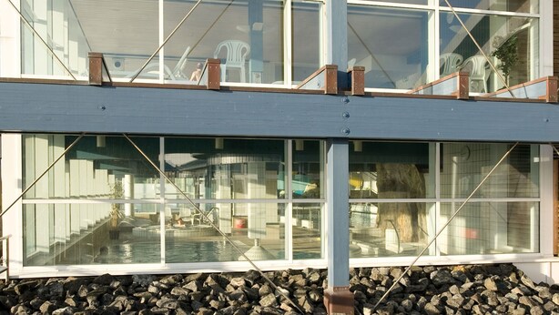 A modern building with large windows overlooking a swimming pool area. - Apartment Strandstrasse 10 / Büsum (Büsum)