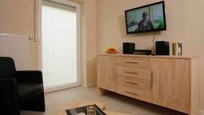 A living room with a television, a wooden cabinet, and a black chair. - Apartment Strandstrasse 10 / Büsum (Büsum)
