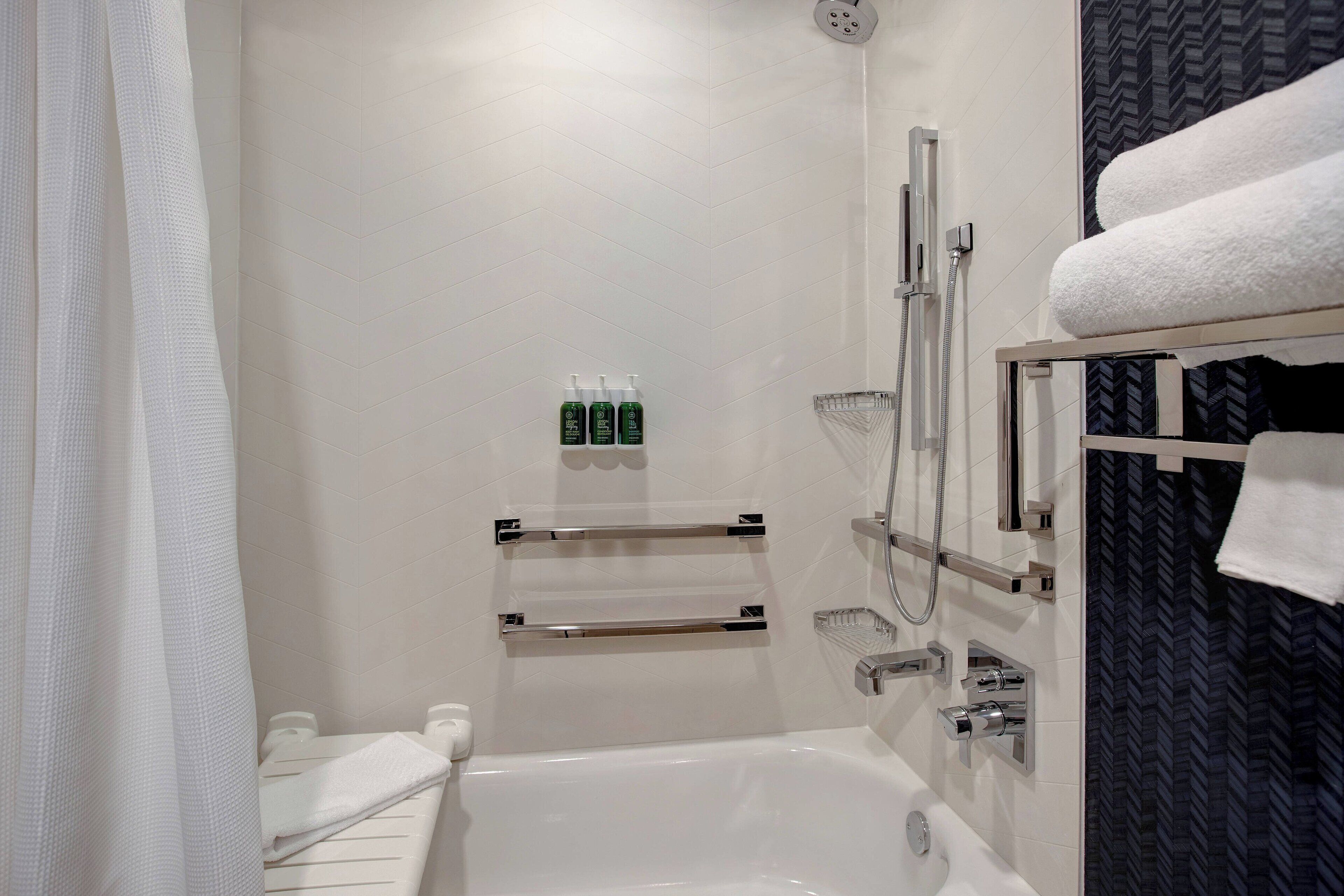 Un baño moderno con bañera, zona de ducha y un perchero para toallas.