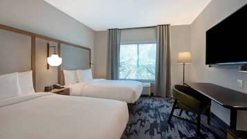 Une chambre d’hôtel avec deux lits, un bureau, un téléviseur à écran plat et une fenêtre avec des rideaux.
