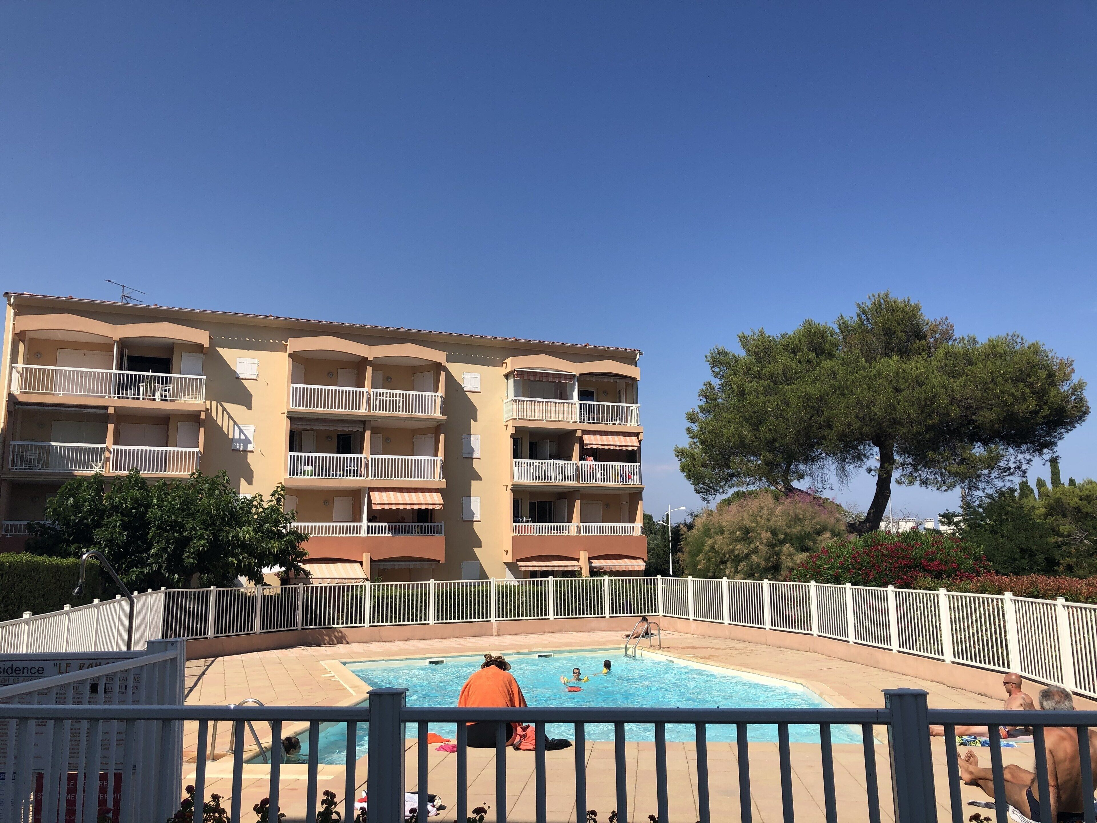 En byggnad med flera våningar, balkonger, en swimmingpool och ett inhägnat område.
