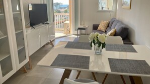 Una sala de estar moderna con comedor, televisor y balcón con vistas.