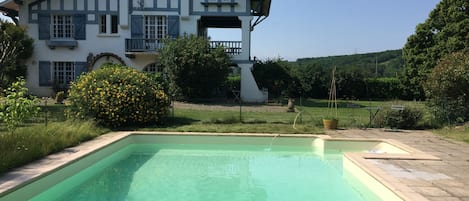 Ein zweistöckiges Haus mit Schwimmbecken im Vordergrund.