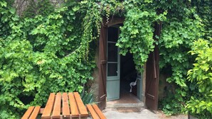 A wooden bench in a garden area with a wooden door and a small step leading into a building. - Gite with pool close to the pyrenees & ancient Abbey of Saint Sever de Rustan (Saint-Sever-de-Rustan)