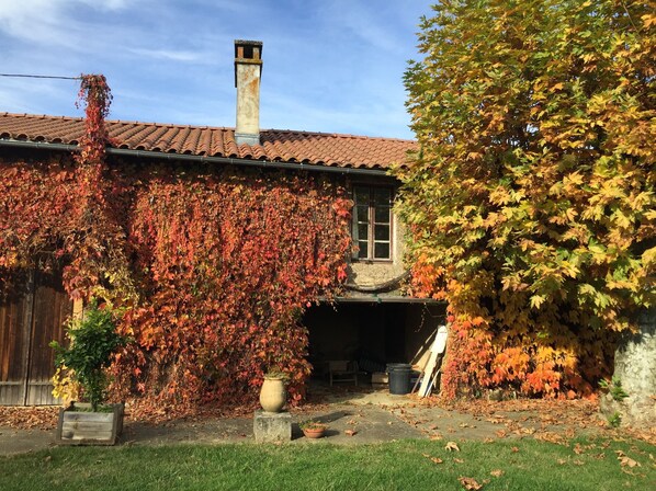 Una casa con techo de tejas, chimenea y muros cubiertos de hiedra.