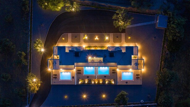 Luchtbeeld van een hotel met een zwembad, meerdere kamers en buitenverlichting.