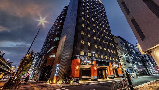Edifici d'hotel modern amb una entrada destacada, grans finestres i una façana ben il·luminada.