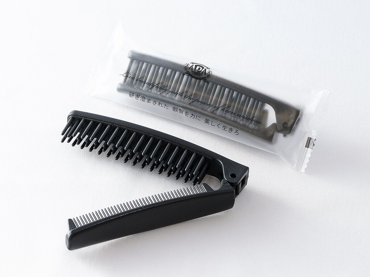 A black comb and a comb case on a white surface.