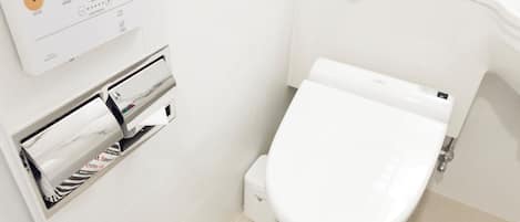 Un baño moderno con inodoro, dispensador de toallas de papel y secamanos.