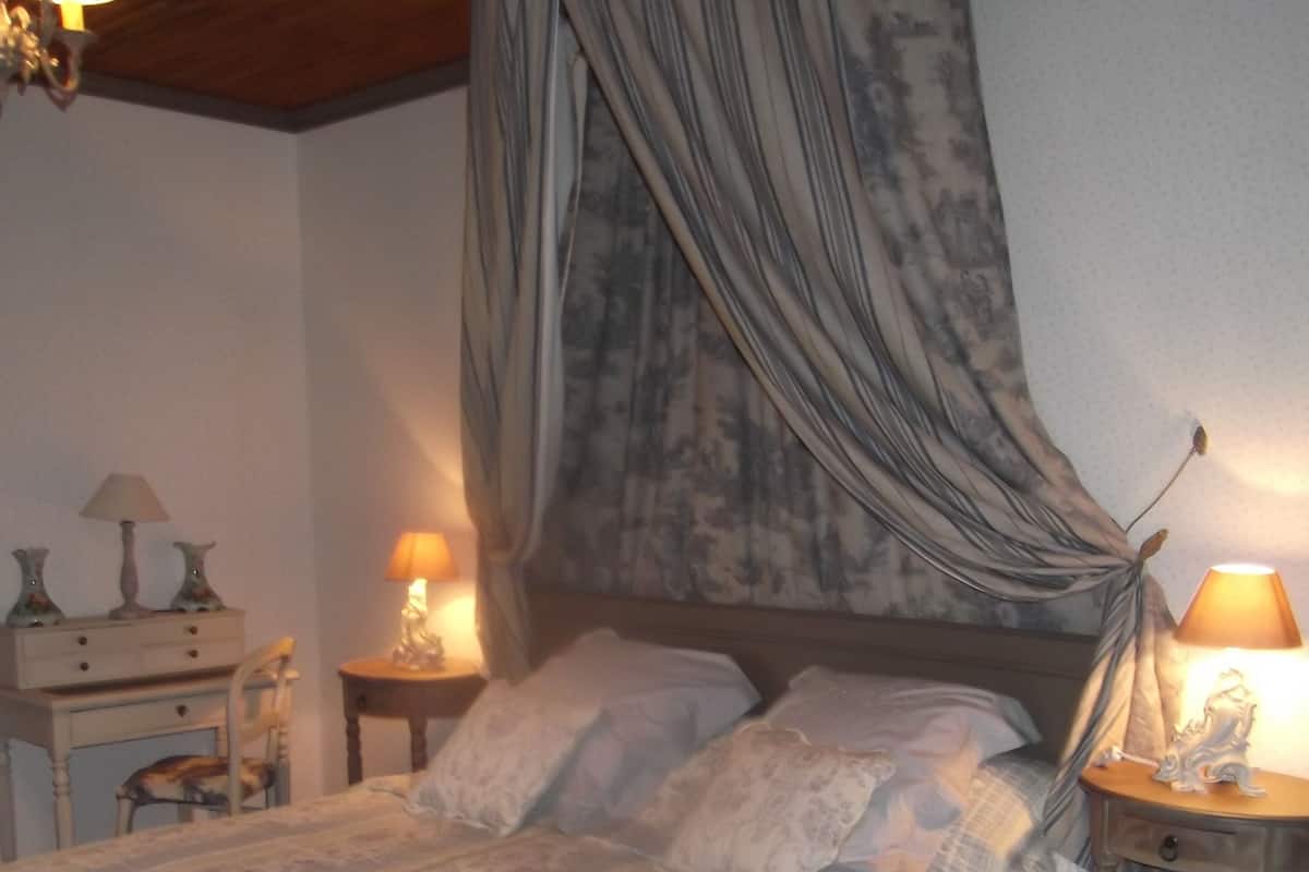 Une chambre à coucher avec un grand lit, une table de chevet avec une lampe et une chaise.